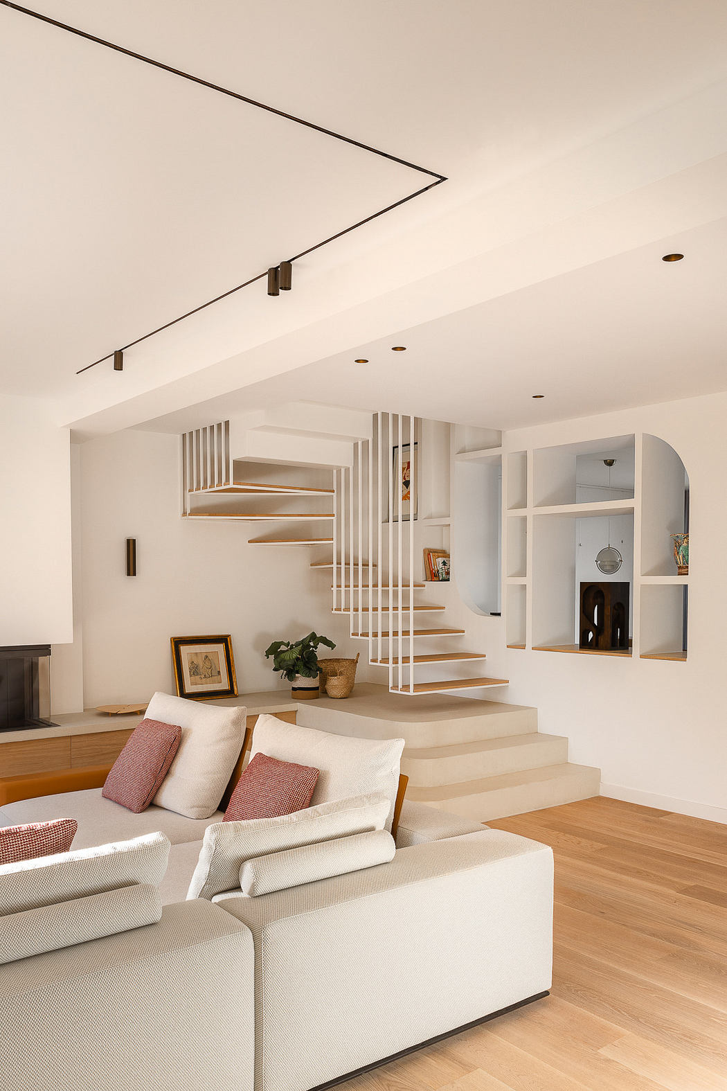 Modern living room with beige sofa and wooden staircase.