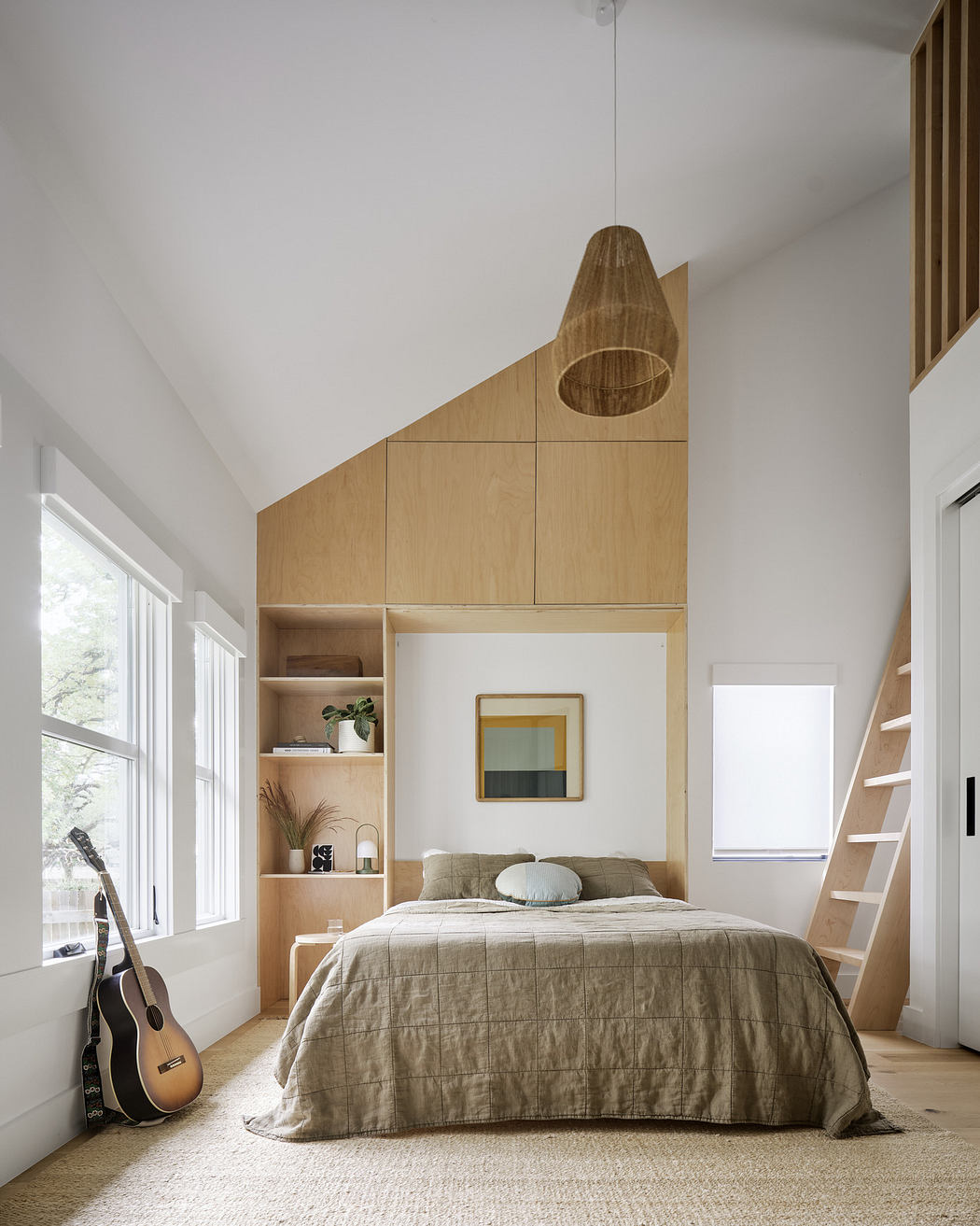 Minimalist bedroom with wooden built-ins, a neutral palette, and a guitar.