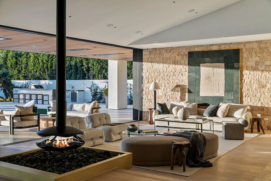 Modern living room with central hanging fireplace and open wall to outdoor view.