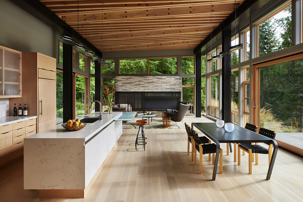 Modern kitchen with light wood cabinets and floor, dining area, surrounded by large windows