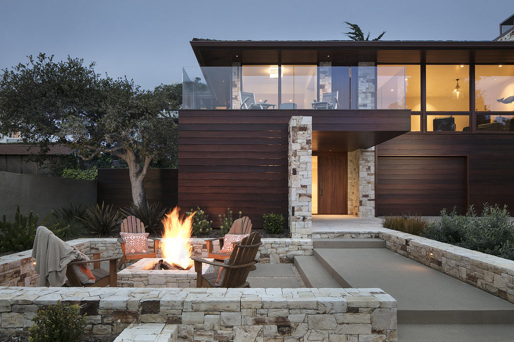 Modern house exterior with fire pit and seating area at twilight.