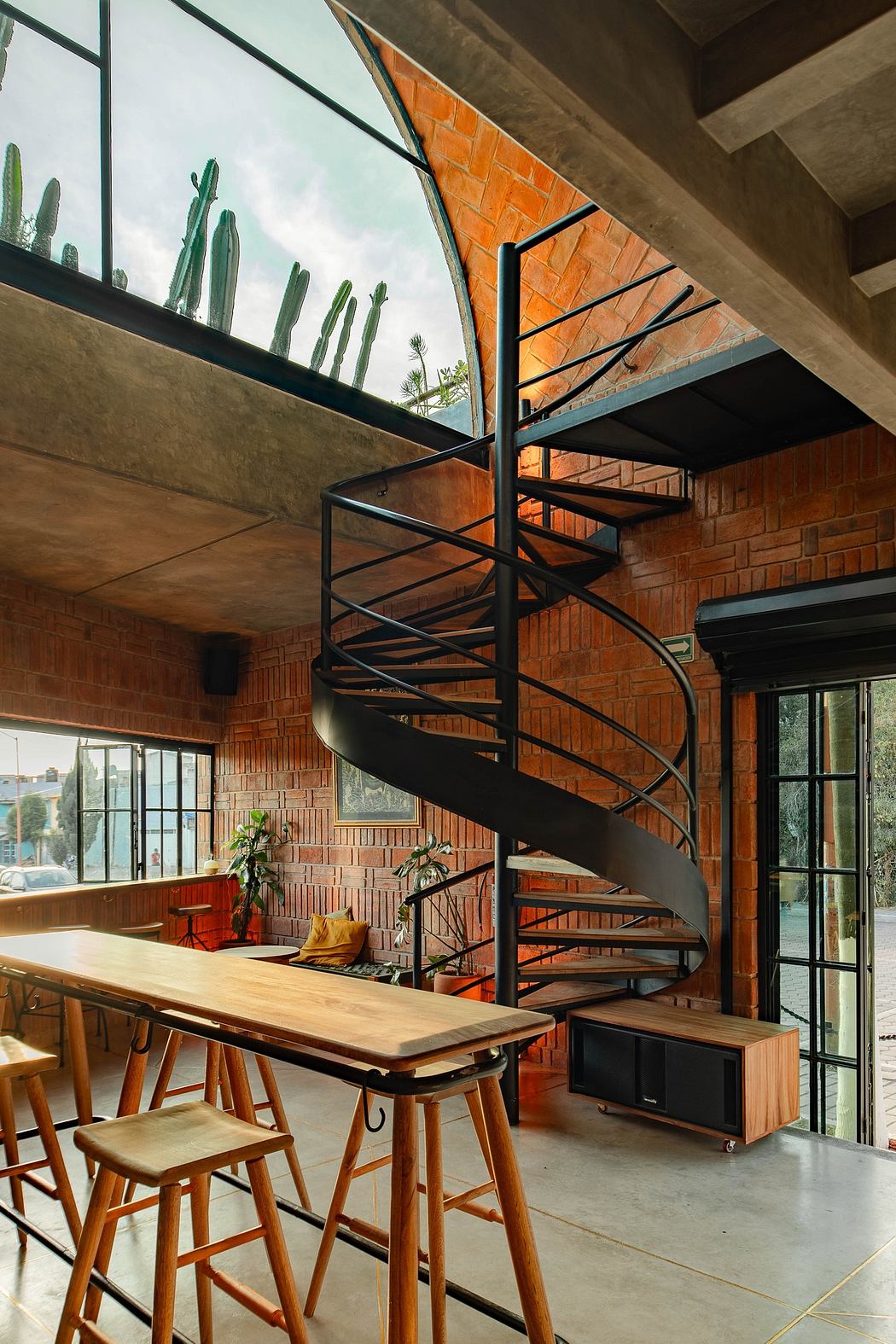 Modern interior with spiral staircase, exposed brick, and large windows.