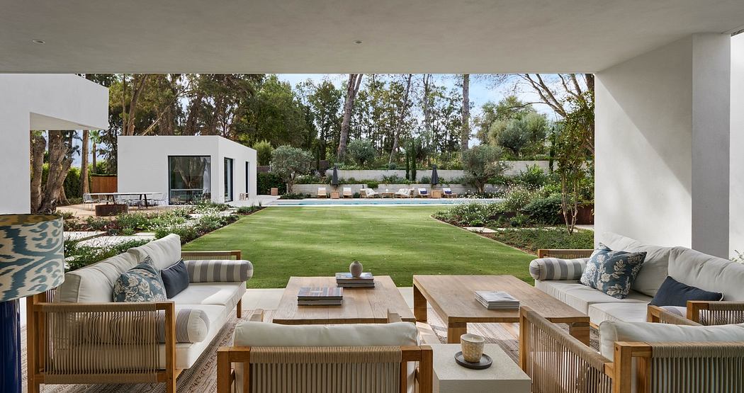 Elegant open patio with stylish outdoor furniture overlooking a pool and garden.