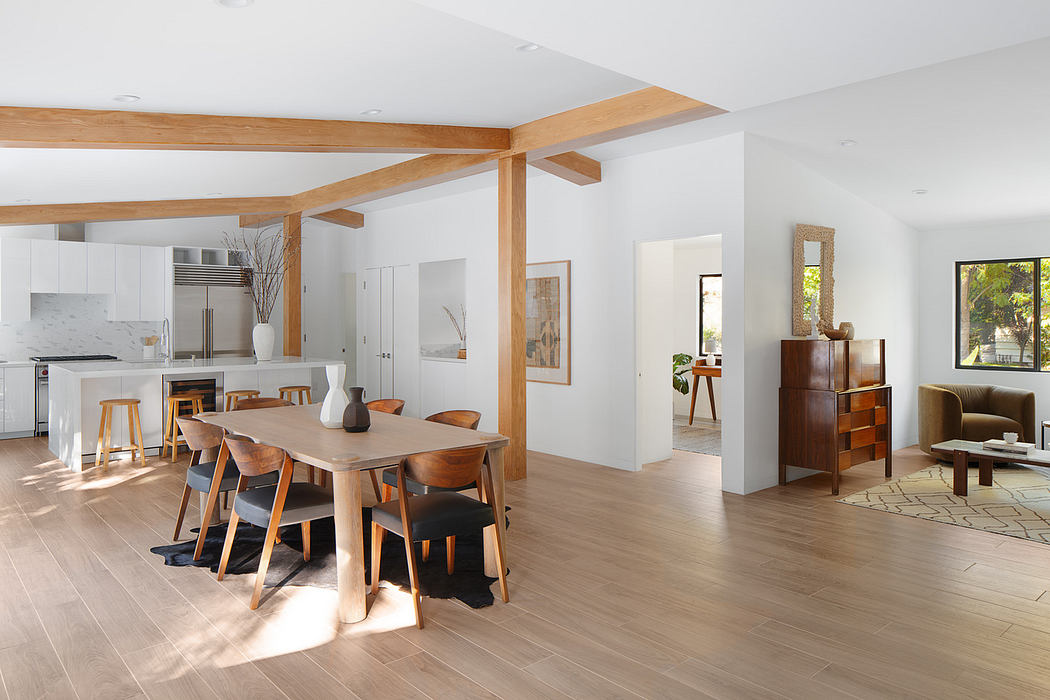 Modern open-plan living space with dining area, wooden beams, and kitchen.