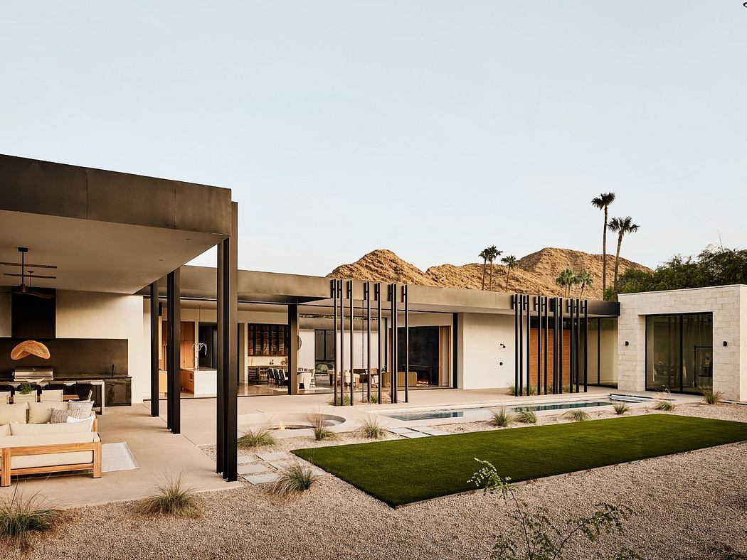 Modern desert home with open patio, expansive windows, and mountain backdrop.