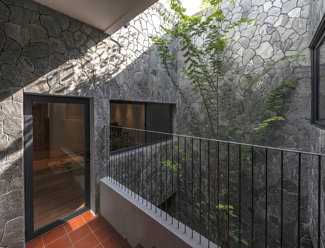 Modern indoor balcony with stone walls, green plants, and glass doors.
