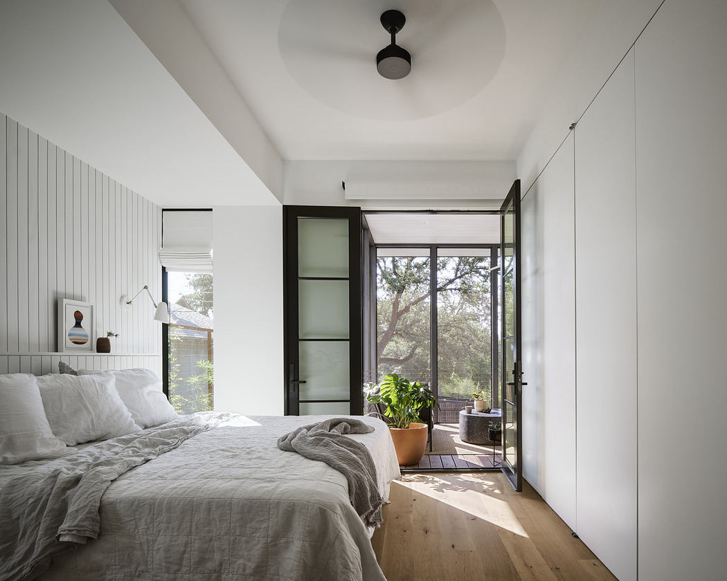 Modern bedroom with white walls, large window, and minimalist decor.