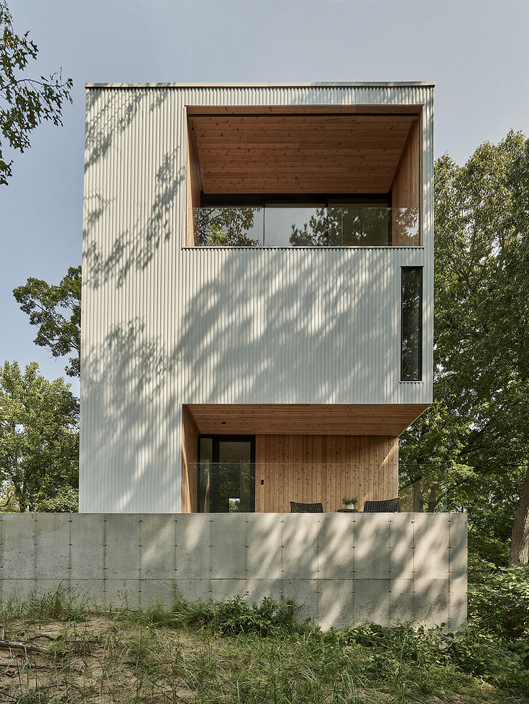 Modern two-story house with a mix of white metal panels and wood cladding.