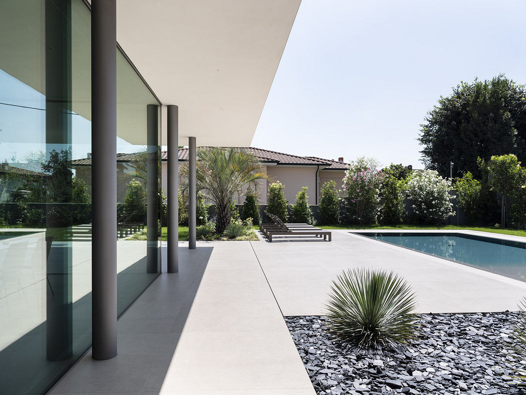 Modern home exterior with poolside patio and glass facade.