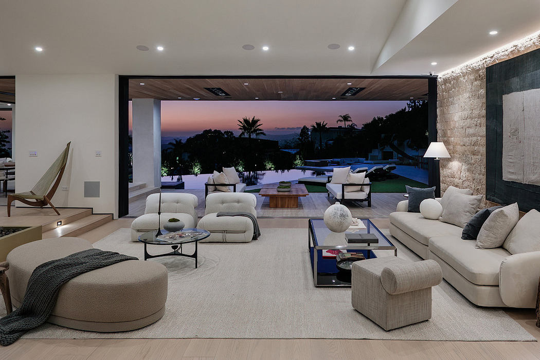 Modern living room with open wall to sunset view over a pool.