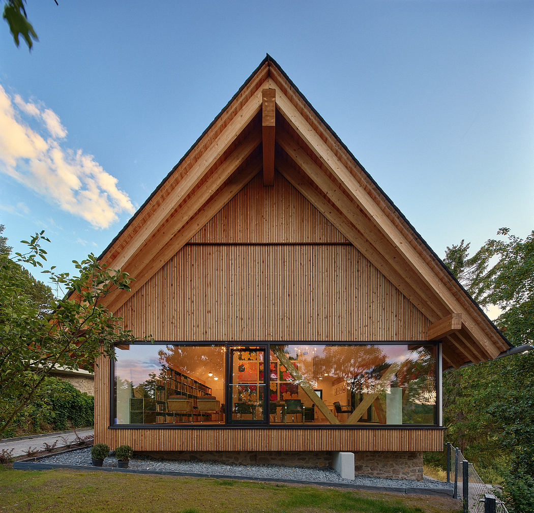 Modern A-frame house with large glass facade during twilight.