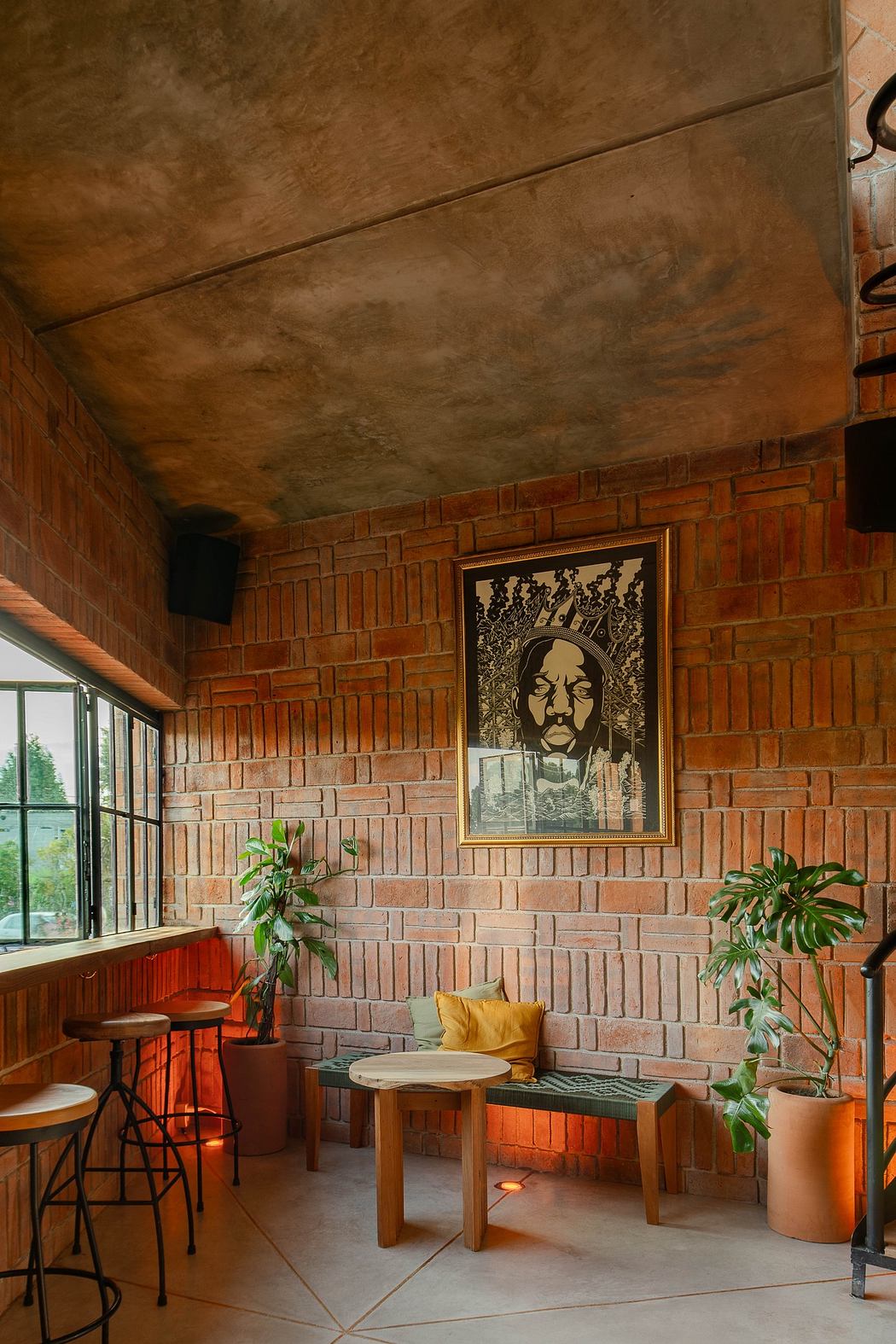 Modern interior with brick walls, bench seating, plants, and artwork.