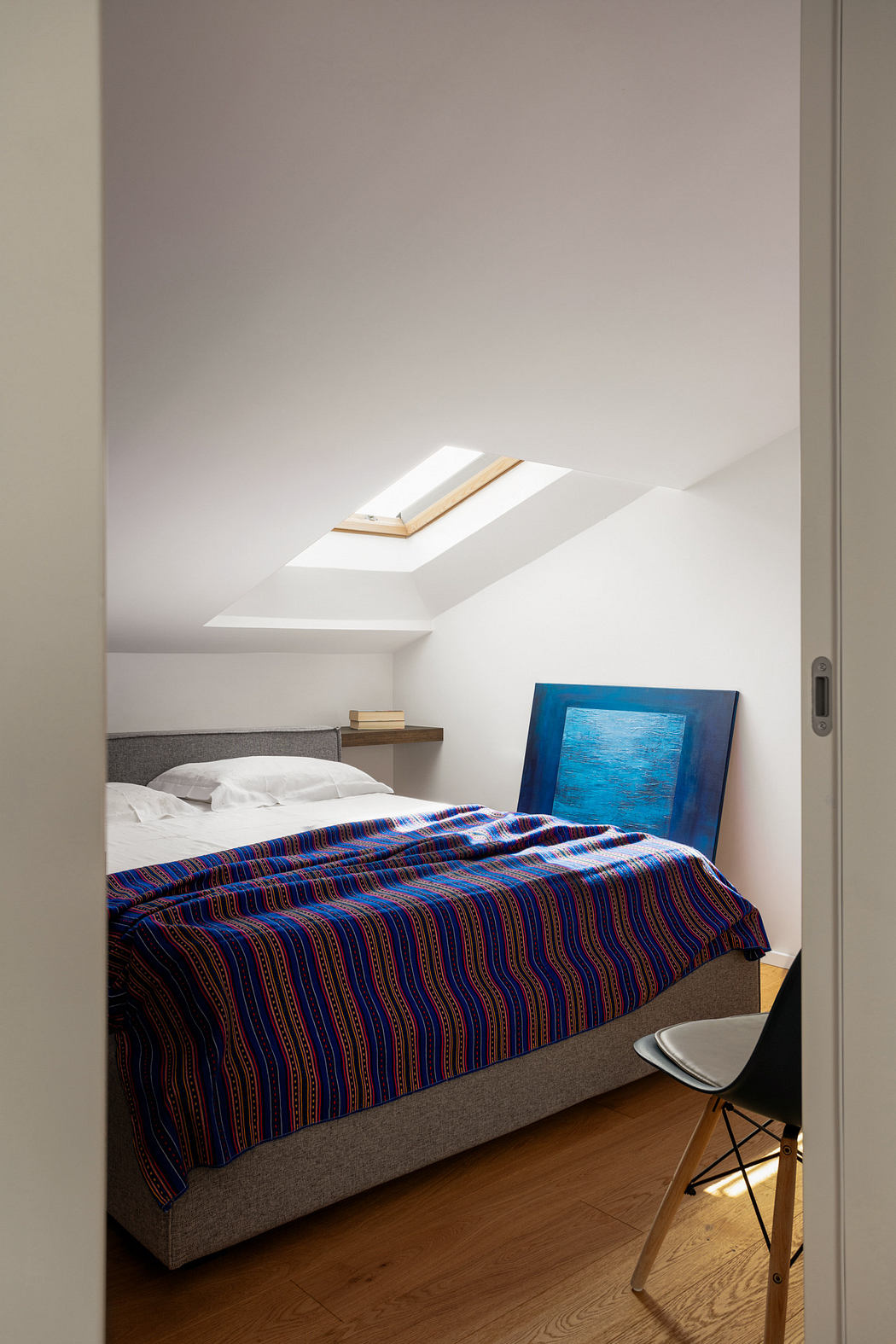 Modern attic bedroom with skylight and minimalist decor.
