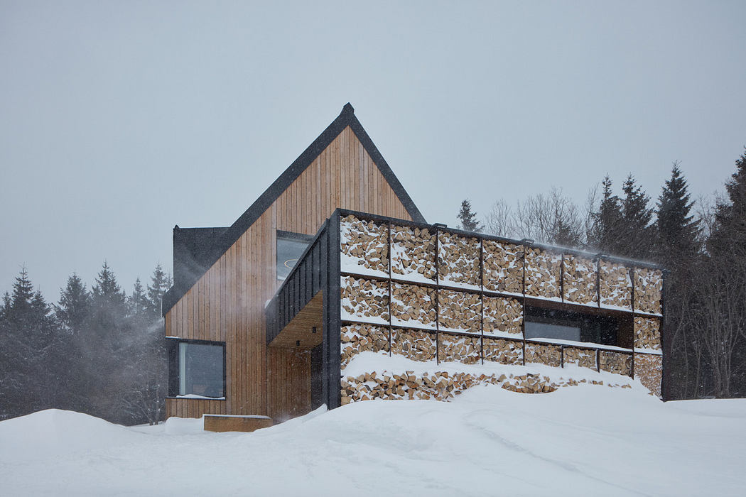 Modern wooden cabin with glass facade in a snowy landscape.