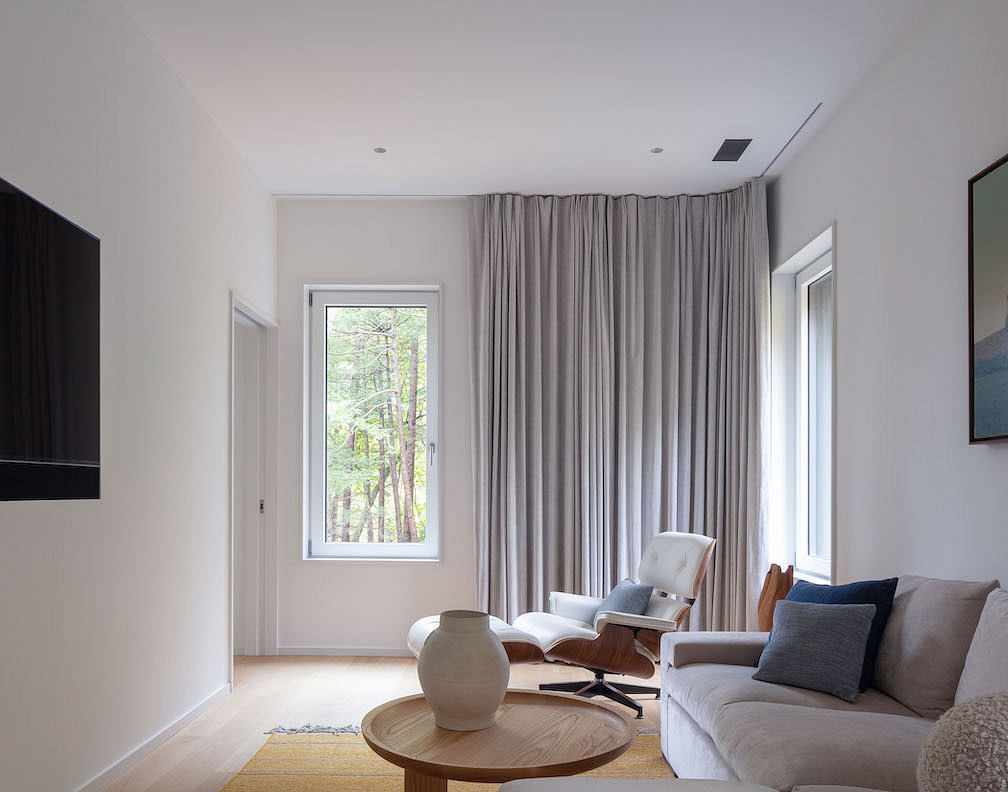 Modern living room with neutral tones and large window with forest view.