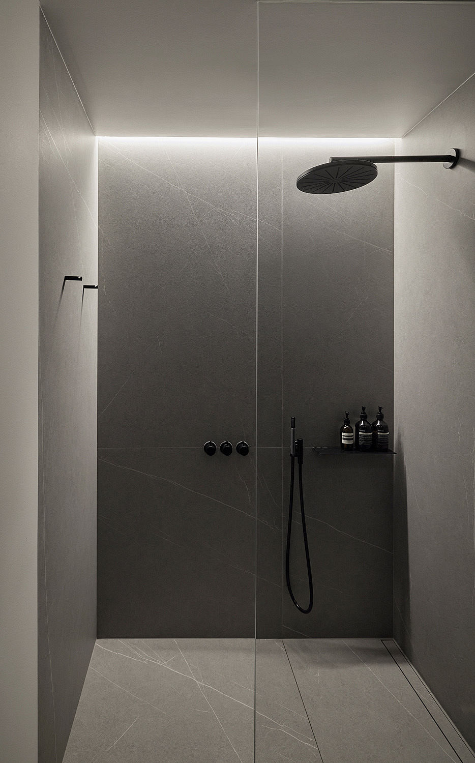 Modern minimalist bathroom with gray tiles and wall-mounted shower.