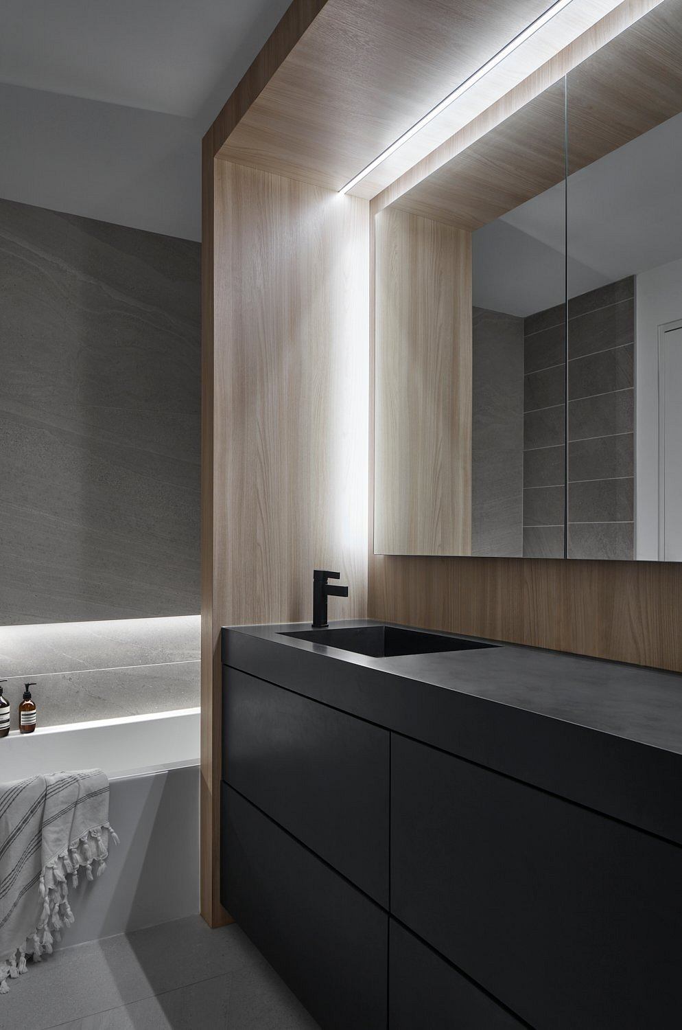 Modern bathroom with sleek black vanity and wooden accents.
