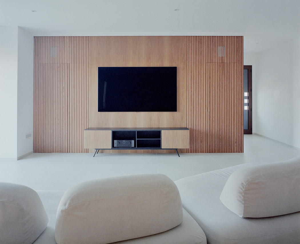 Minimalist living room with wooden wall paneling and mounted TV.