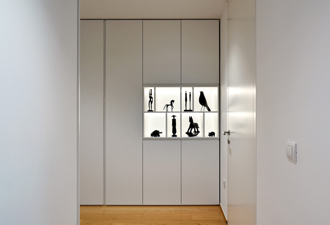 Minimalist interior with a built-in white cabinet displaying black sculptures.