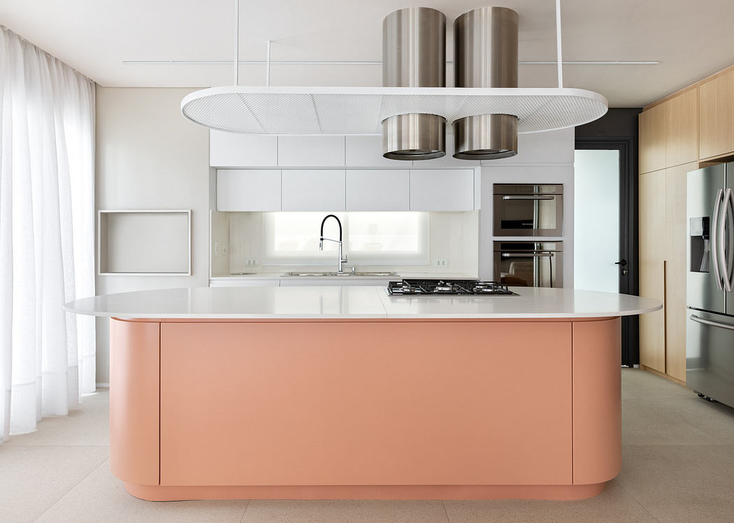 Modern kitchen with a pink central island and stainless steel appliances.