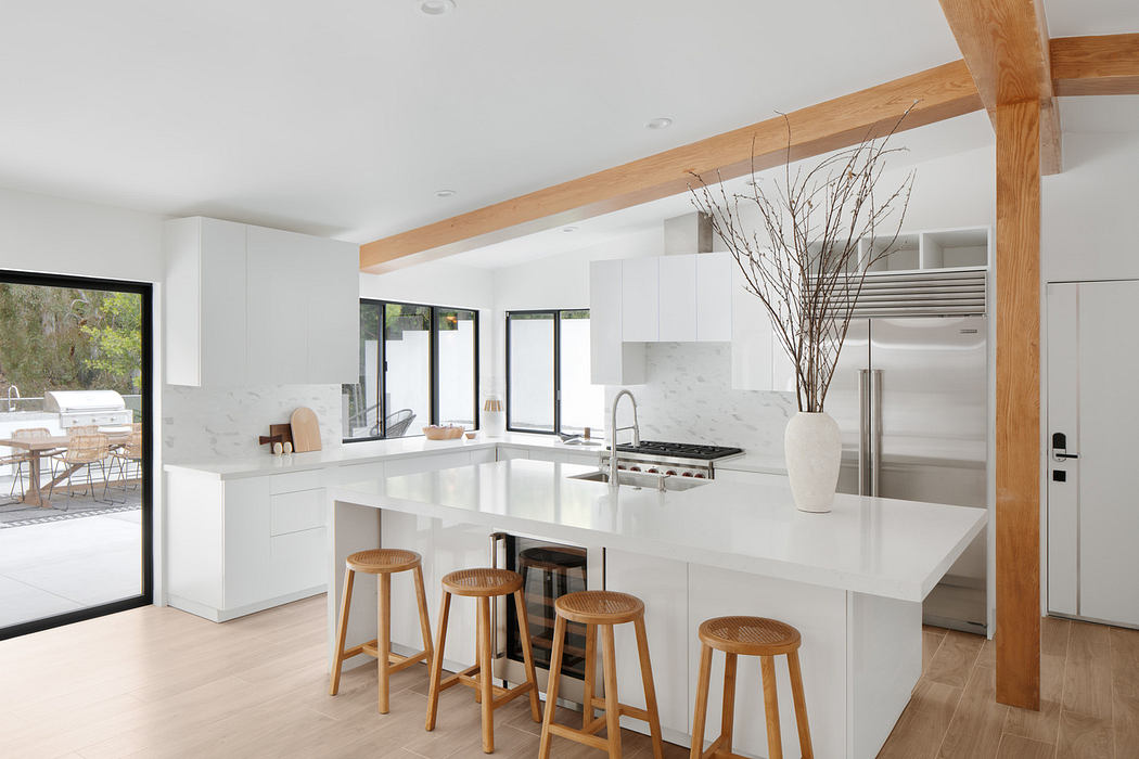 Modern kitchen with white interiors, wooden accents, and a central island.