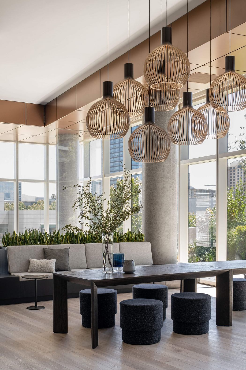 Modern lobby with wooden pendant lights, plush seating, and greenery.