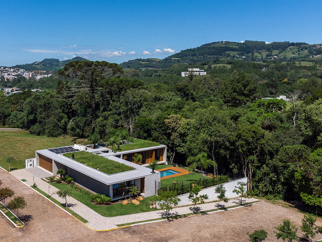 Modern single-story house with green roof and pool amidst lush greenery.
