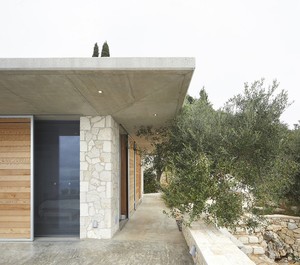 Modern house exterior with concrete, wood paneling, and natural stone.
