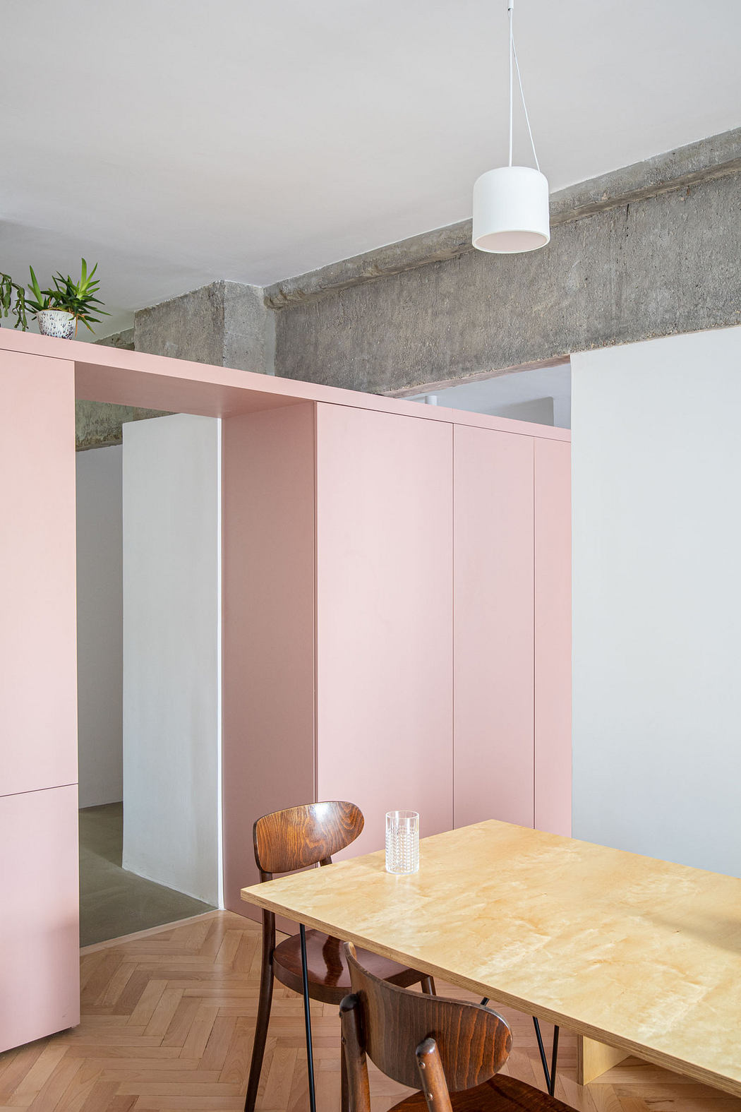 Modern room with pink sliding panels, wooden table, chairs, and pendant light.