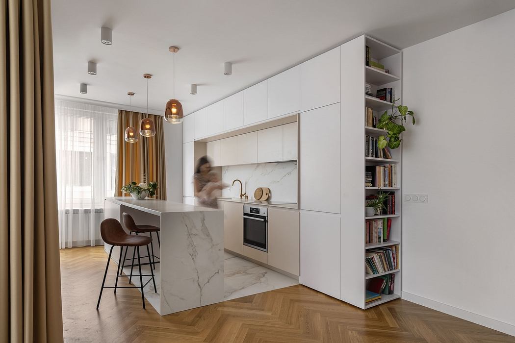 Modern kitchen with white cabinetry, marble island, and wooden floors.