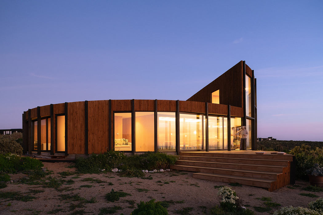 Modern wooden house with large windows at dusk.