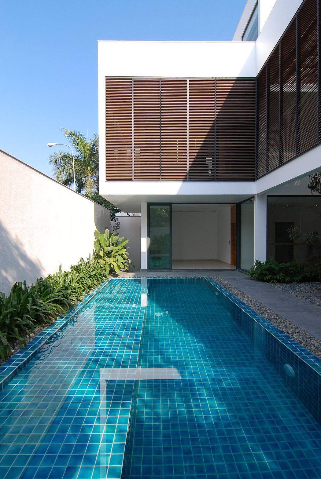 Modern house with a long rectangular pool and wooden-panelled facade.