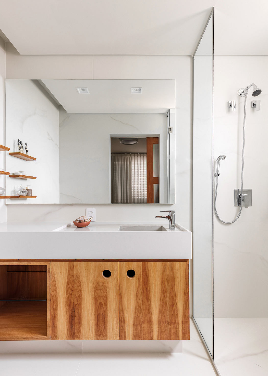 Modern bathroom with wooden vanity, white sink, and glass shower.