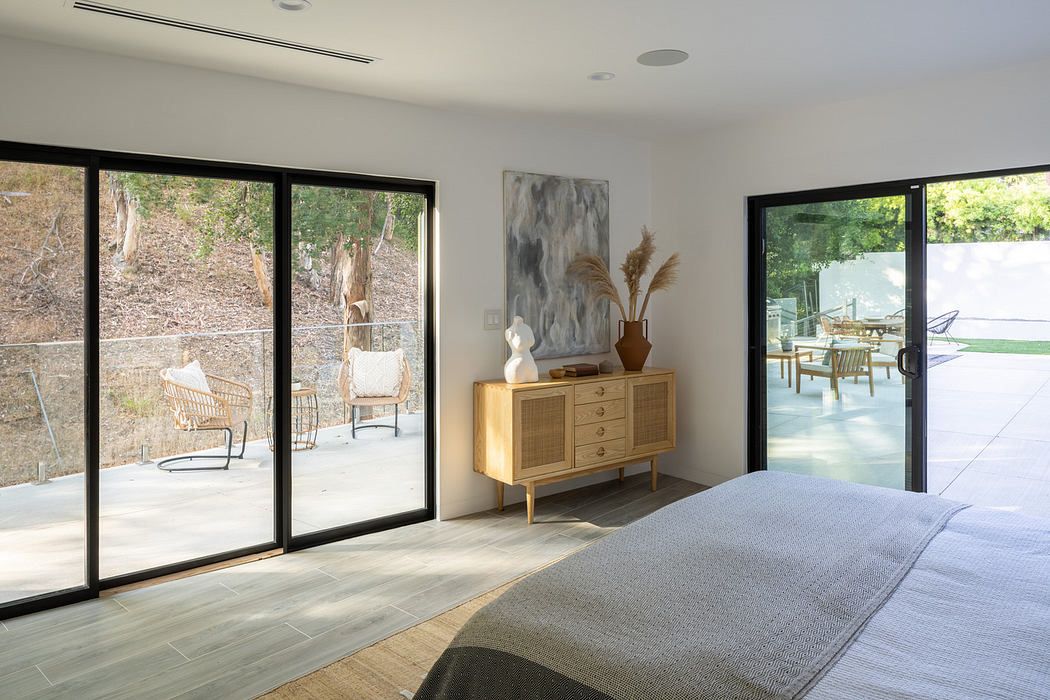 Minimalist bedroom with large windows overlooking nature.