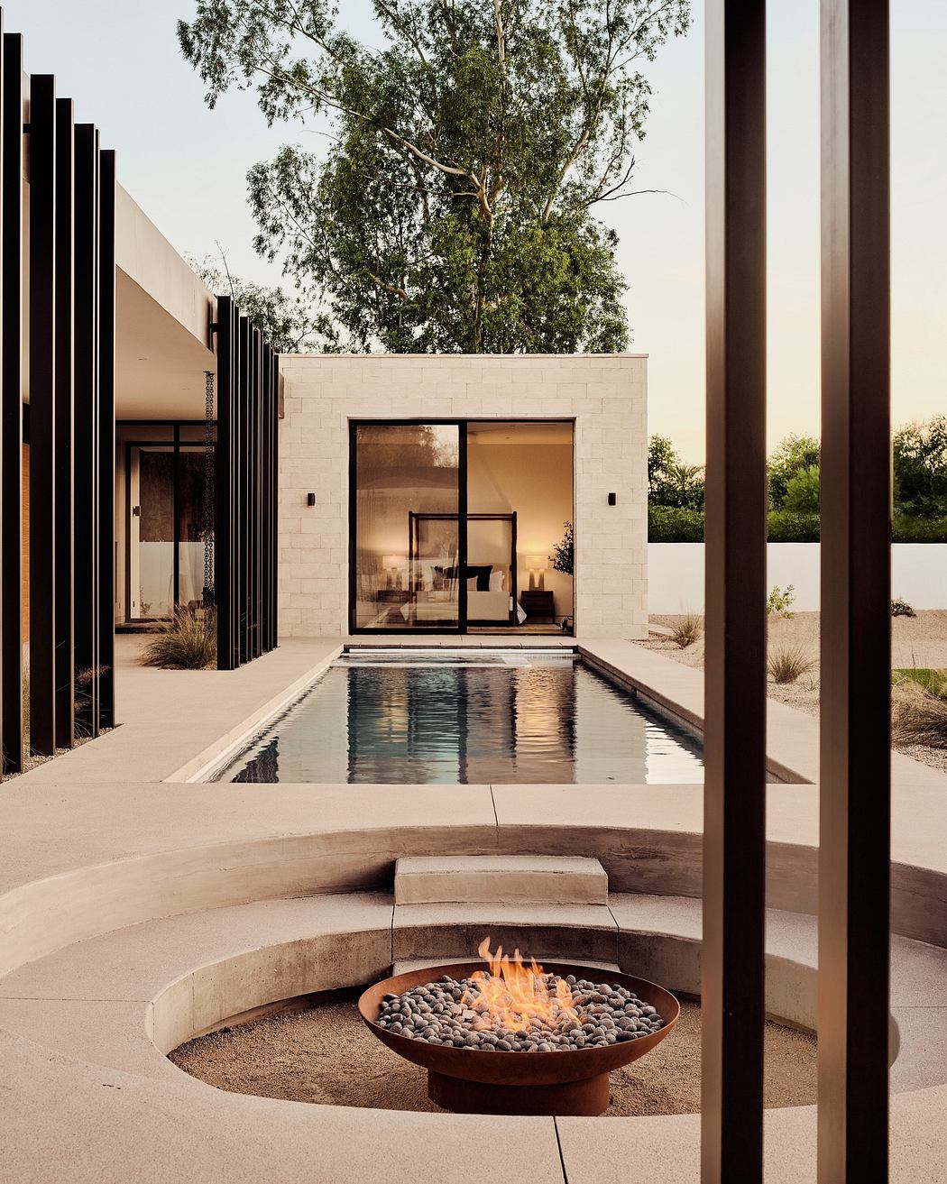 Modern backyard with pool, fire pit, and minimalist building.
