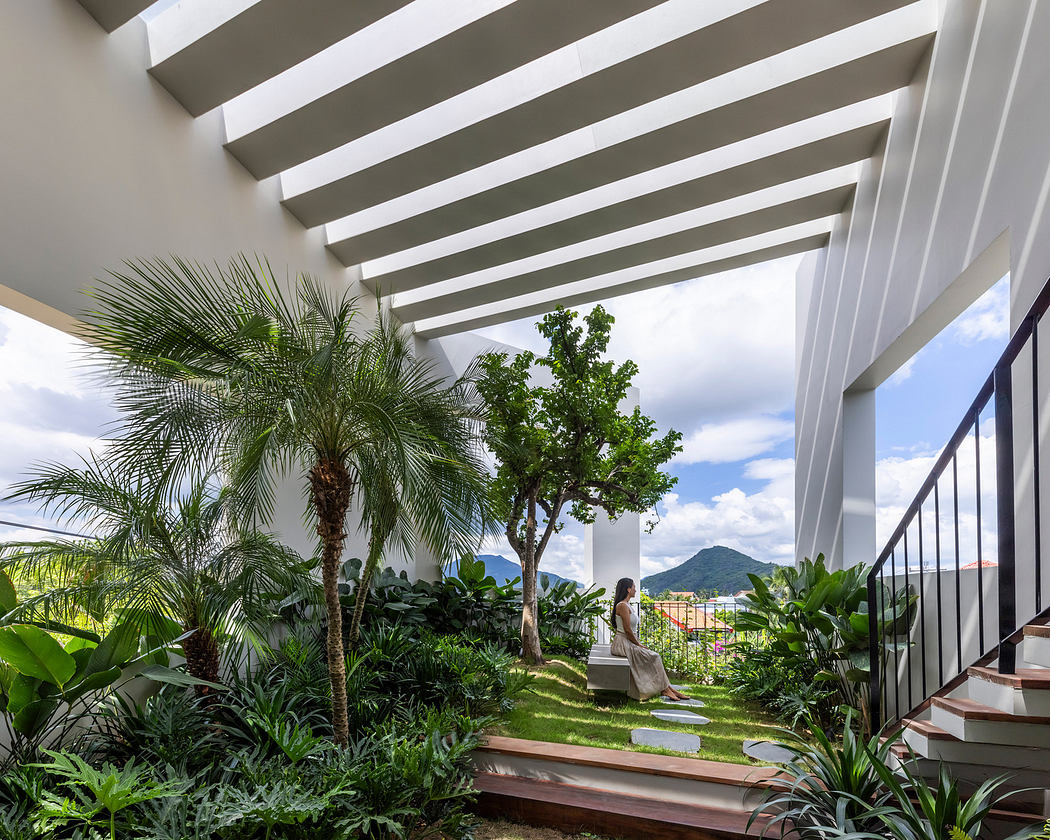Modern terrace with white pergola, lush greenery, and mountain view.