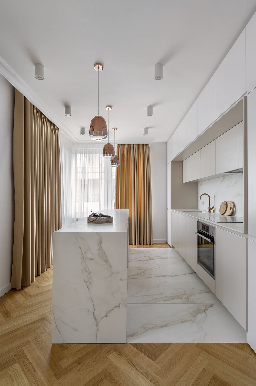 Modern kitchen with marble island and wooden floors.
