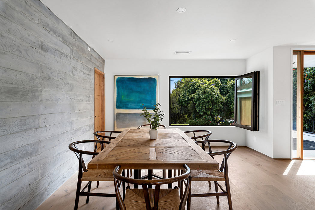 Modern dining room with large table, abstract art, and garden view.