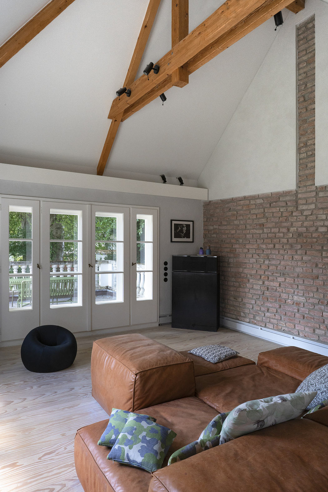 Modern living room with exposed beams, brick wall, and leather sofa.