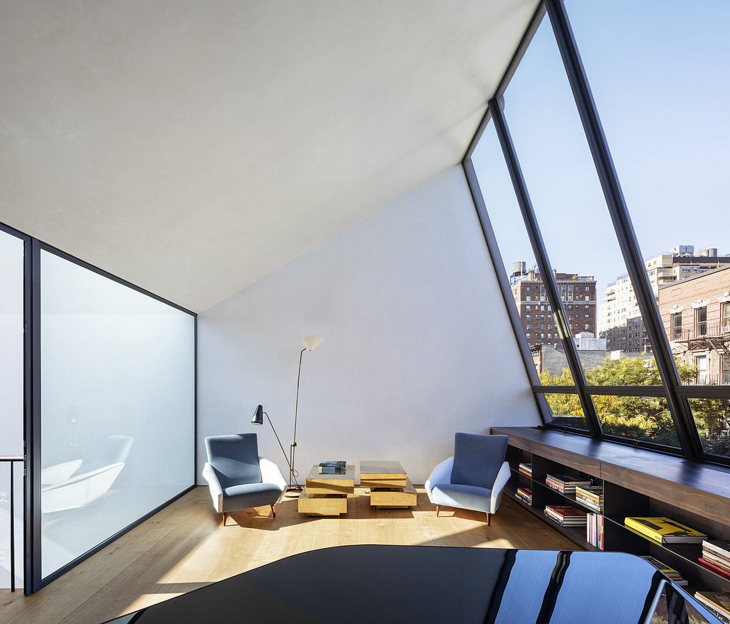 Minimalist interior with large angled window, city view, and modern furniture.