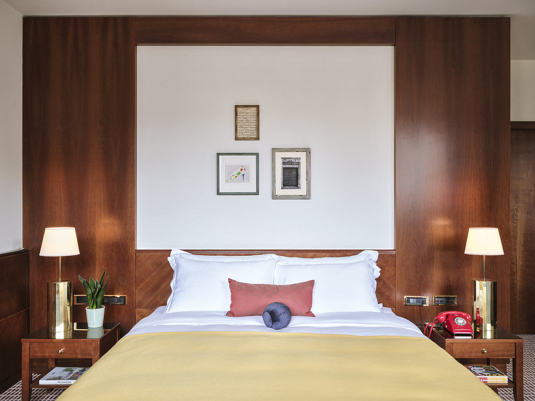 Modern bedroom with white bedding, wooden headboard, and accent pillows.
