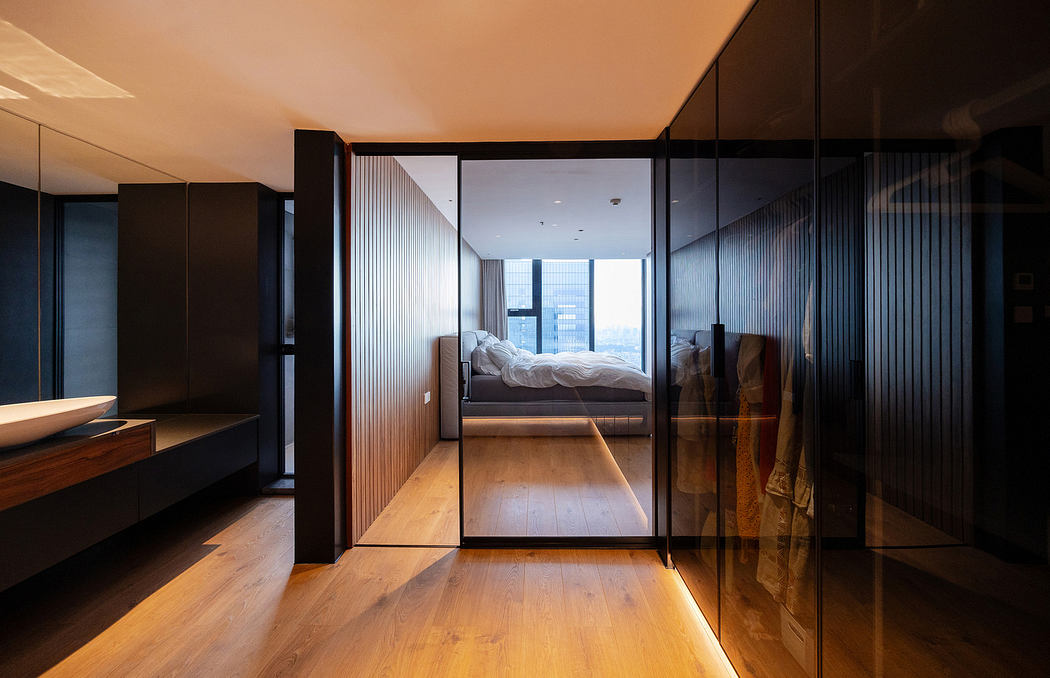 Modern apartment interior with sleek black glass partitions and wooden flooring.