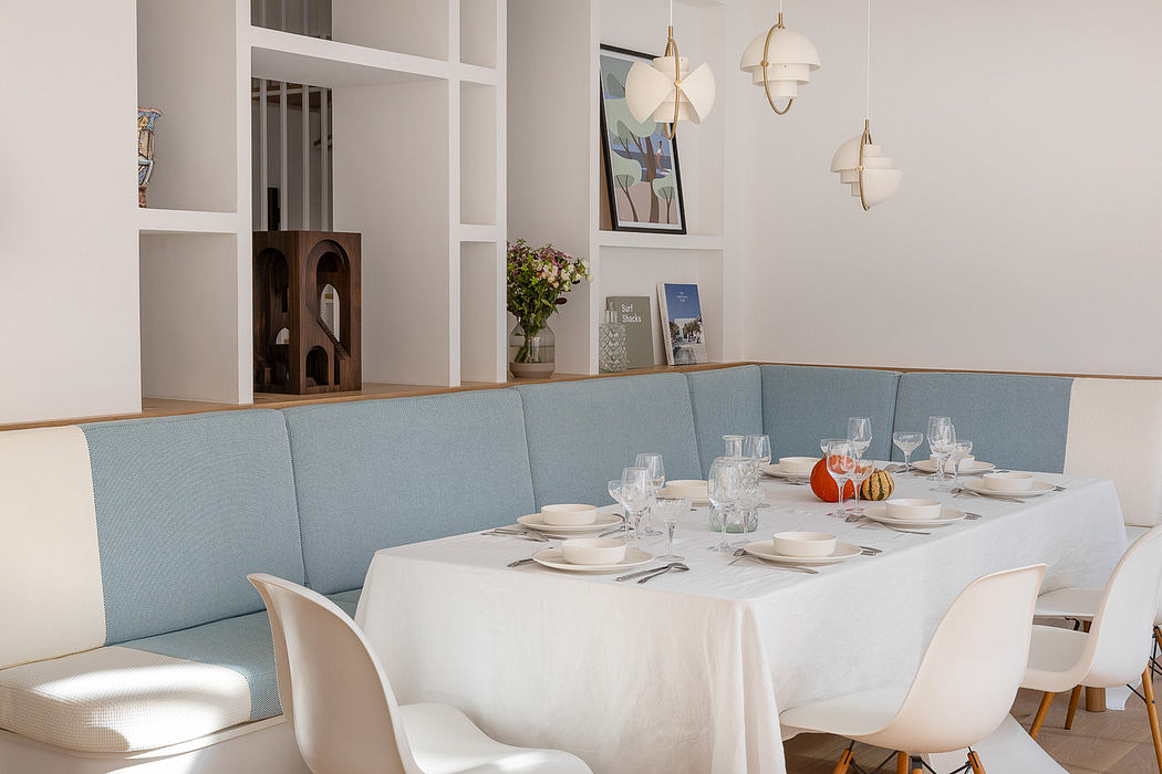 Modern dining room with blue corner bench and white table set for a meal.