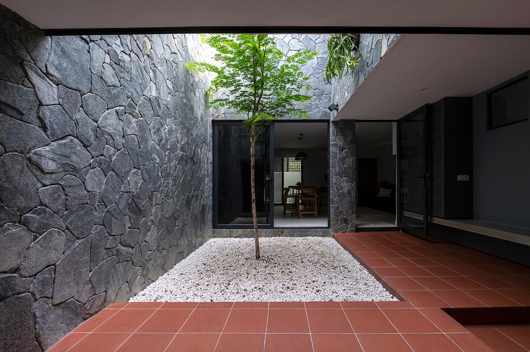 Modern courtyard with stone walls, a single tree, and terracotta tiles.
