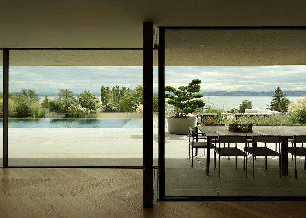 Modern dining room with large glass wall overlooking a pool and scenic view.