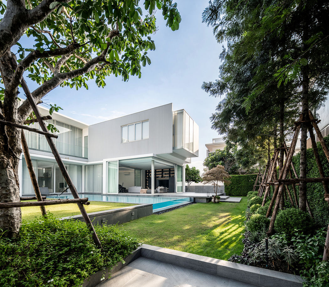 Modern house with large windows, pool, and landscaped garden.