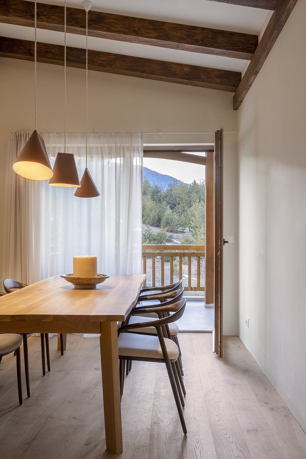 Modern dining room with wooden table, chairs, pendant lights, and a view of