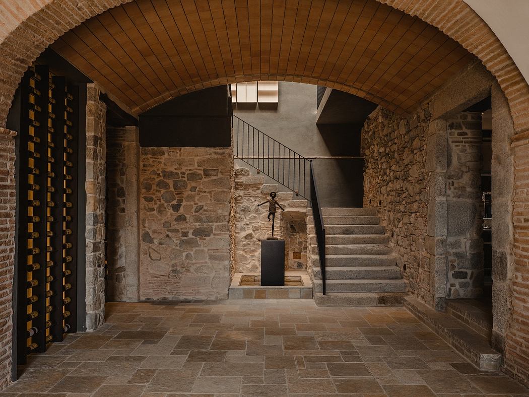Stone archway leading to stairs with a modern sculpture and wine rack on the left