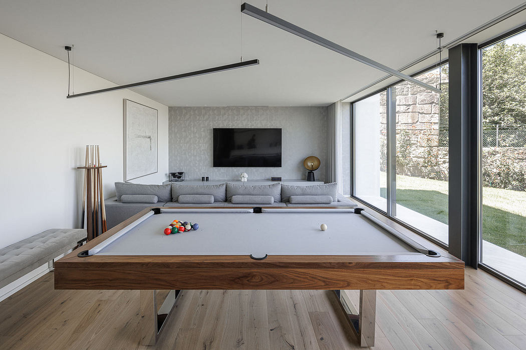 Modern living room with pool table, sofa, and large windows.