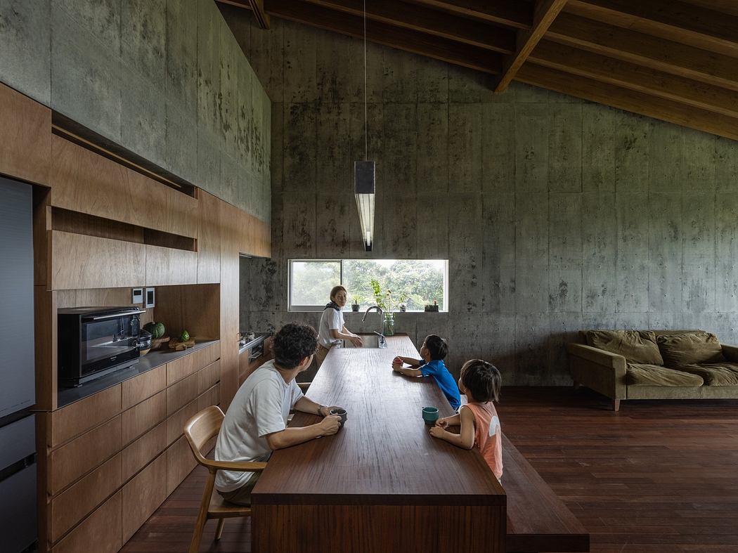 Modern kitchen with wooden cabinetry, concrete walls, and a family gathered around an